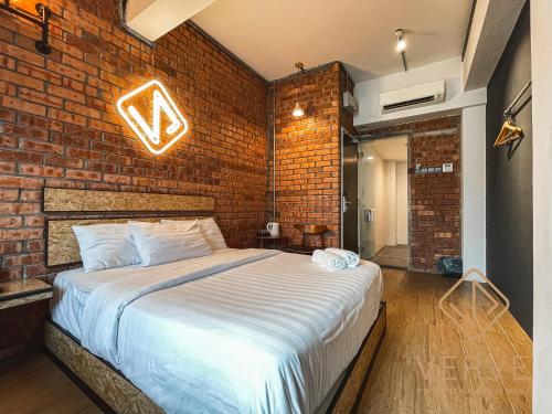 怡保Brick Box Ipoh by Verve的一间带砖墙和大床的卧室