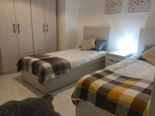 圣保罗湾城Bugibba Sunrise View Modern Apartment的一间卧室配有两张床和一个带床头柜的梳妆台。