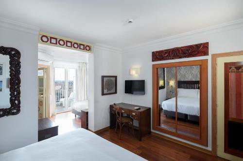 菲格拉斯Sercotel Hotel President的一间卧室配有一张床和一张带镜子的书桌