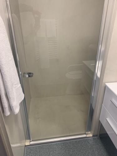 塔塔班亚Szelim Motel的浴室里设有玻璃门淋浴