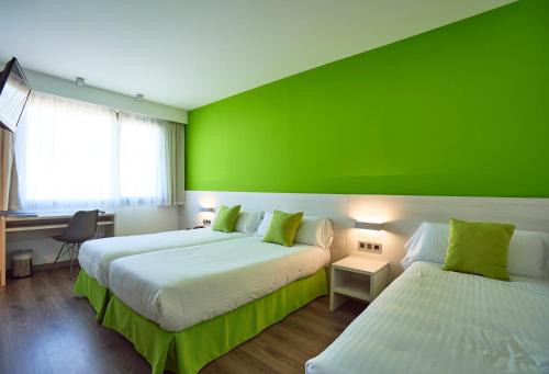 罗列特海岸Hotel Julimar的绿墙客房的两张床