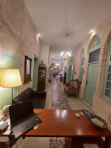 拿撒勒Al Bishara Guest House的客厅配有一张木制桌子上的笔记本电脑