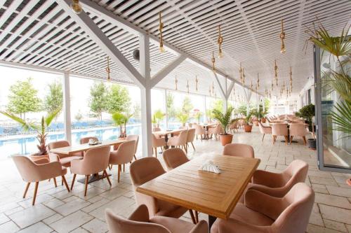 北马马亚-讷沃达里Nautic Luxury Club的一间带桌椅的餐厅和一个游泳池