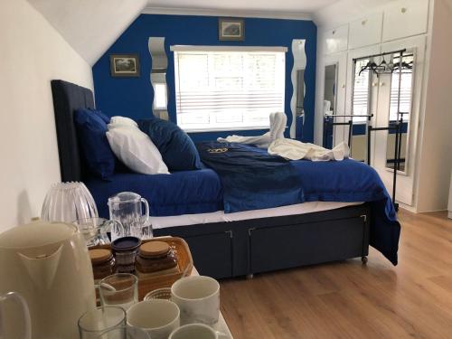 ShidePonders End的蓝色的卧室配有床和带眼镜的桌子