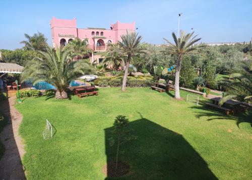 BerrechidEqui Palace & SPA Near Aeroport的一座棕榈树大院子和一座粉红色的建筑