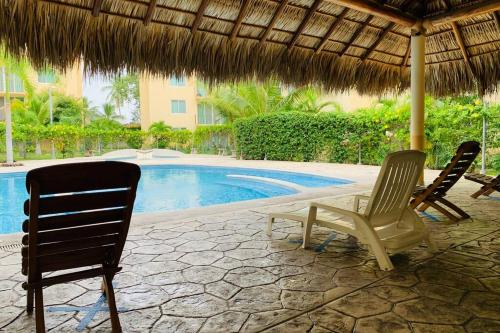 圣克鲁斯华特库El Colorín, a condo in the heart of Huatulco的游泳池旁的两把椅子和一把遮阳伞