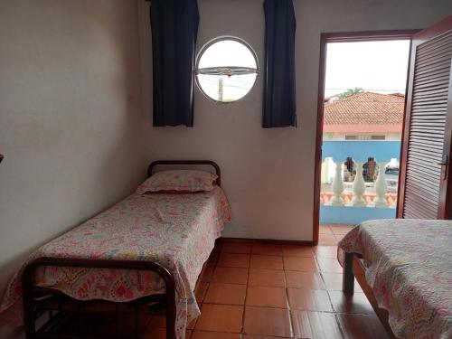 伊利亚孔普里达Casa Azul no Centro Ilha Comprida的一间卧室设有两张单人床和一个窗户。
