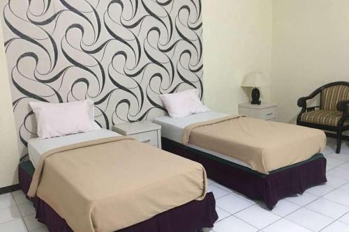 WonokromoSMESA Edotel Syariah Surabaya Mitra RedDoorz的酒店客房,配有两张床和椅子