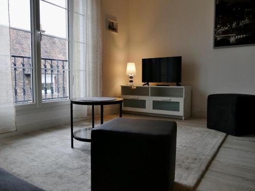 法莱斯Appart'hôtel Chambrappart的客厅配有电视、桌子和椅子