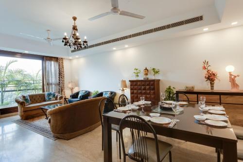 新德里Ishatvam-4 BHK Private Serviced apartment with Terrace, Anand Niketan, South Delhi的用餐室以及带桌椅的起居室。