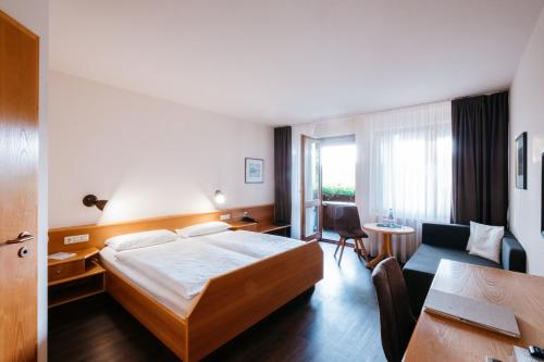 Gomadingen冬季餐厅兰德酒店的酒店客房配有一张床、一张书桌和一张沙发。