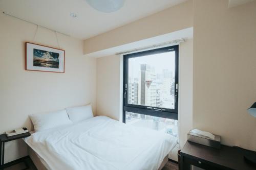 东京unito SHIODOME的卧室设有白色的床和大窗户