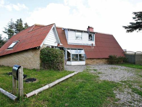 Trans7 person holiday home in Lemvig的一座红色屋顶的房子和一个院子