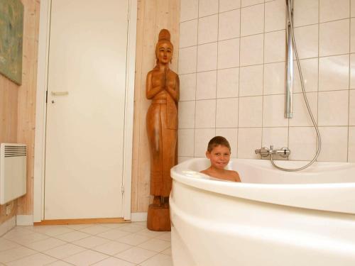 吉利勒杰6 person holiday home in Dronningm lle的坐在雕像旁的浴缸里的男孩