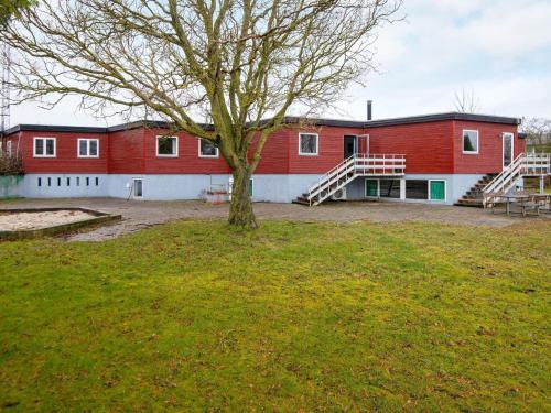 诺德堡30 person holiday home in Nordborg的一座大红色的建筑,院子里有一棵树