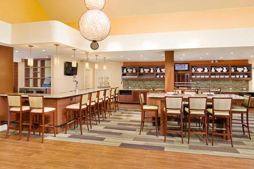 埃尔塞贡多Hyatt House LAX Manhattan Beach的餐厅设有大型酒吧,配有木桌和椅子