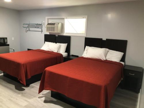 North Camellia AcresBay Inn Hotel的客房设有两张带红色床单的床和窗户。