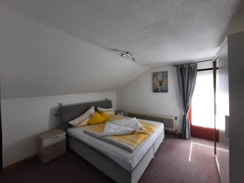 绍滕斯Haus Waldfrieden的一间卧室配有一张带黄色枕头的床和一扇窗户