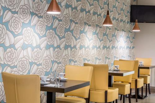 兰斯Sure Hotel by Best Western Reims Nord的用餐室配有桌子和黄色椅子