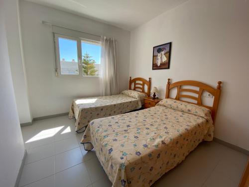 阿尔考斯布里Apartamentos Serenamar Altamar的一间卧室设有两张床和窗户。