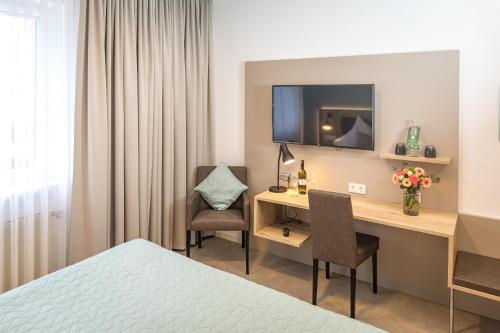 Nieder-SaulheimHotel Lehn的酒店客房配有书桌和电视。