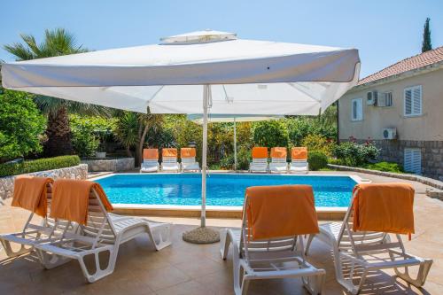 莫鲁纳特Apartments Vidak的白色遮阳伞、2把椅子和游泳池