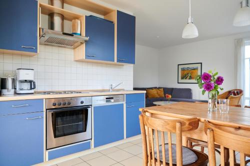 奥斯特巴德里克Sonneneck Rerik的厨房配有蓝色橱柜和木桌