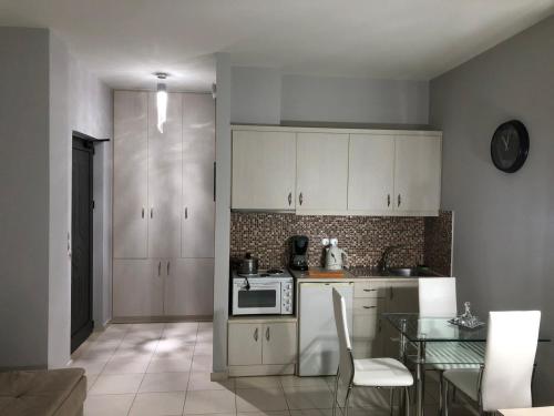 罗达奇诺Peristeres Appartments的厨房配有白色橱柜和玻璃桌