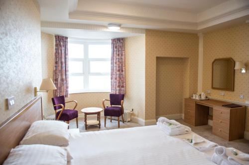 波斯考尔海畔酒店的酒店客房,配有一张床、一张桌子和椅子