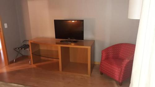 巴西利亚Apartamento no condomínio do Brasil 21 Suites的一张木桌、一台电视和一张红色椅子