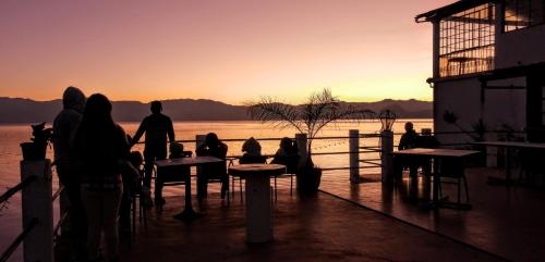 圣佩德罗拉拉古纳Mikaso Hotel的一群坐在桌子旁观看日落的人