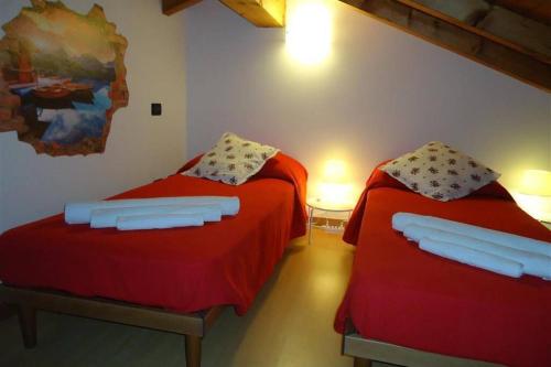 梅纳焦Piscina e vistalago CroceMenaggio CIR 013145-00318的红色床单的客房内的两张床