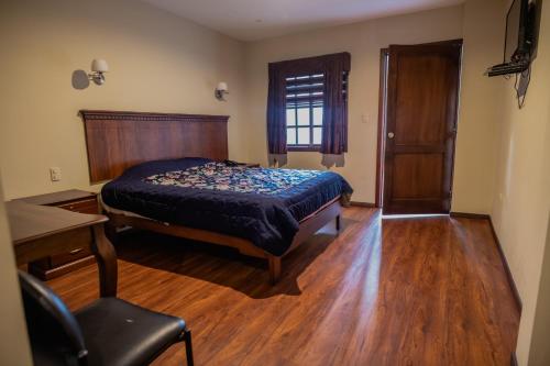 昆卡Suites & Hotel El Quijote的一间卧室配有一张床、一张书桌和一个窗户。
