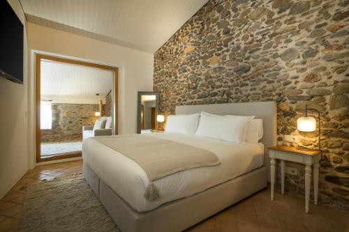 巴利-略夫雷加Hotel Mas del Sol的一间卧室设有一张大床和石墙
