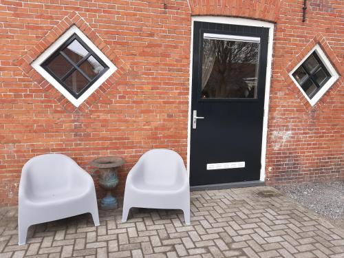 BafloAppartementen Hoek 2的两把白色椅子,在砖砌建筑前,有一扇门