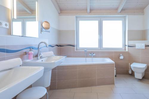 达格比尔Ferienhaus Stockente的一间带两个盥洗盆、浴缸和卫生间的浴室