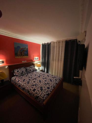雅温得Homestay Appartement 2 chambres的一间小卧室,配有床铺和红色的墙壁