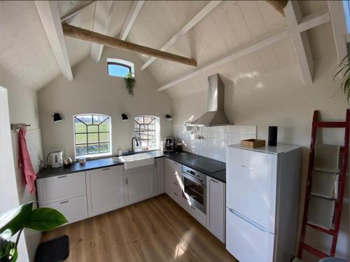 Vakantiehuis in Friesland met boot的厨房配有白色橱柜和白色冰箱。