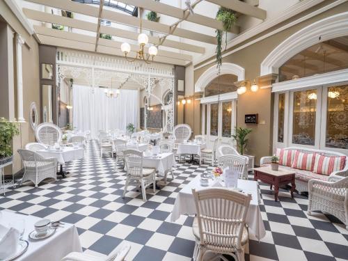 霍巴特哈德利东方酒店的餐厅设有白色的桌椅和 ⁇ 格地板