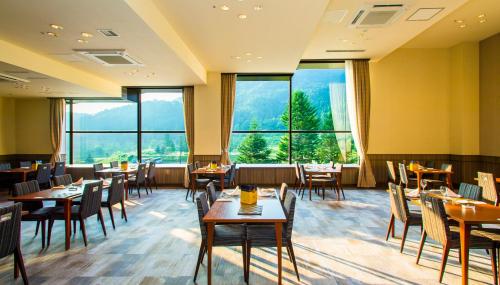 信浓七巧板酒店的餐厅设有桌椅和大窗户。