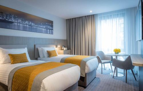 泰恩河畔纽卡斯尔Maldron Hotel Newcastle的酒店客房设有两张床和一张桌子。