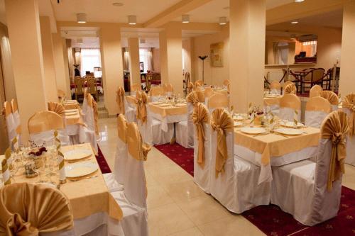 克卢日-纳波卡阿雷酒店的宴会厅配有白色的桌椅和弓形