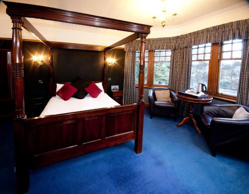邓弗里斯利文德尔酒店的一间卧室配有一张天蓬床、一把椅子和一张桌子