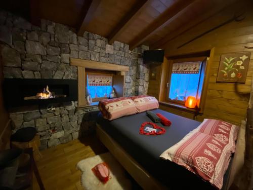 皮亚扎托雷ALLA STALLA Suite & Chalet的小屋内设有一间带壁炉的卧室和两张床