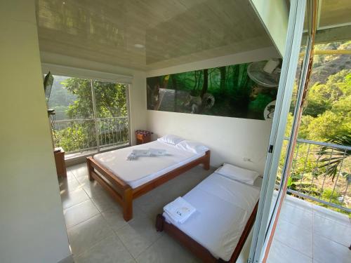 NorcasiaEcohotel Campo Alegre Norcasia Caldas的一间带两张床的卧室和一个阳台