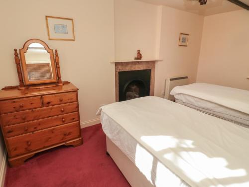 伍勒Rose Cottage的一间卧室设有两张床和一个壁炉