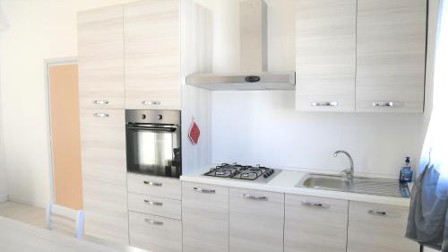 普罗斯西托角Appartamento a Punta Grossa con giardino的厨房配有白色橱柜和炉灶烤箱。