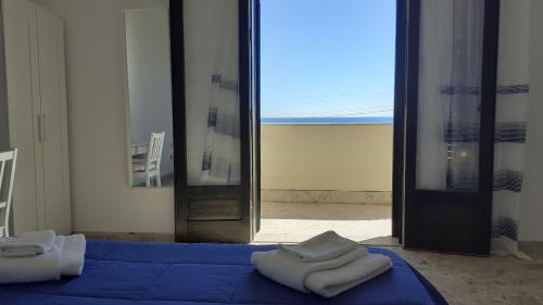 马里内拉Bahari Beachfront Aparthotel Selinunte的一间设有蓝色床和毛巾的房间