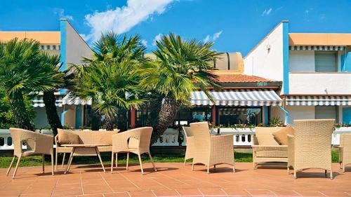 毕博纳的码头Hotel Riva Etrusca的棕榈树庭院里的桌椅