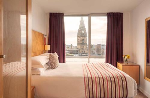 利物浦普瑞米尔利物浦套房酒店的一间卧室配有一张床,窗户配有钟楼